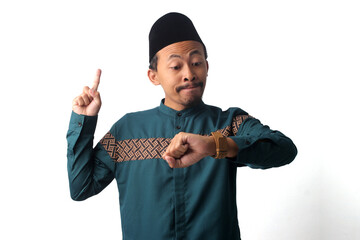 Young Asian Muslim man pointing his finger up while checking the time, anticipating iftar, the time to break fasting during Ramadan. Isolated on white background, time management, anticipation concept