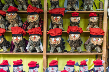 A market stall display featuring rows of wooden Tio de Nadal logs with red hats and painted faces waiting to be sold.