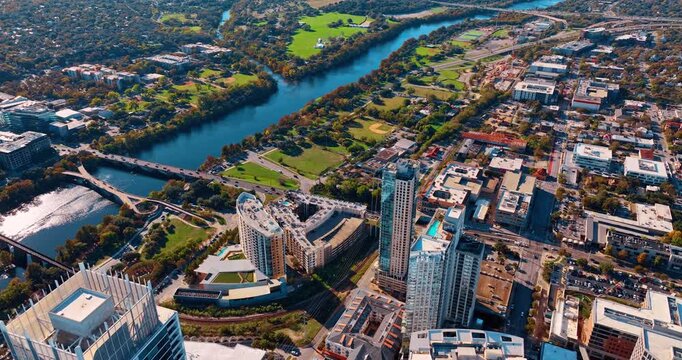 Lots of cars ride by the bridge over the river and road along it. Drone footage over the picturesque waterfront of the Colorado River in Houston, Texas, USA.