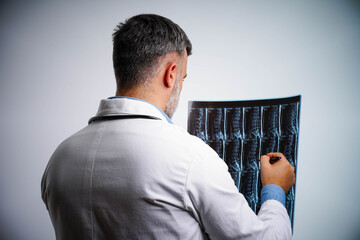 Male physician reviewing spinal MRI scan with patient, back view in hospital