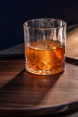 whiskey cocktail served on the rocks with dramatic lighting served on a wooden surface.