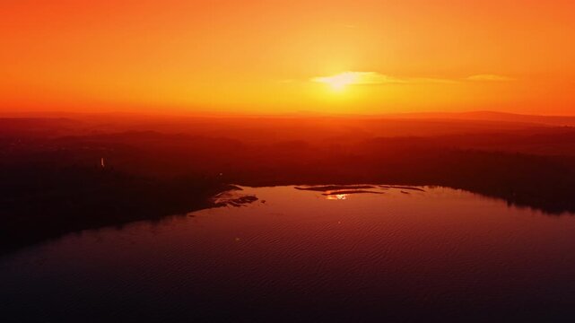 Sunset over calm reservoir and islands. Low sun above water with sandbars and forest horizon, warm evening mood.
