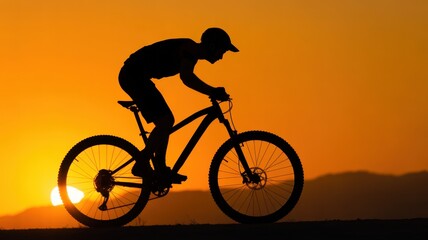 Obraz premium Silhouette of a Cyclist: A dynamic silhouette of a cyclist, set against a fiery sunset, epitomizes freedom and adventure on two wheels, evoking a sense of motion and the thrill of the open road.