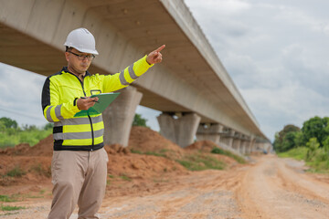 An Asian male engineer works at a motorway bridge construction site,Civil worker inspecting work on crossing construction,Supervisor working at high-speed railway construction site