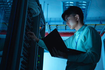 Computer engineer is setting up network in server room,Systems Maintenance Technician,Male engineer working in server room at modern data center