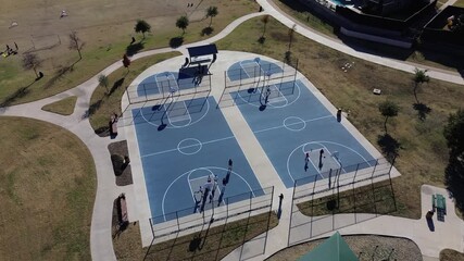 Four full-sized blue courts enclosed by fencing anchor the Coppell, Texas park sports zone. Shaded structure, soccer goals, and scattered trees enhance the upscale layout recreational diversity