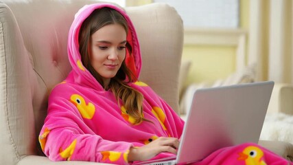 Woman working on laptop in pink wearable blanket hoodie with duck print, sherpa fleece loungewear, oversized comfort, cozy home workspace, soft texture, casual remote work, indoor warmth