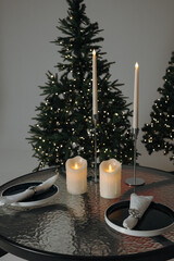 Table setting for a romantic Christmas or New Year's dinner with a Christmas tree in the background. Vertical photo