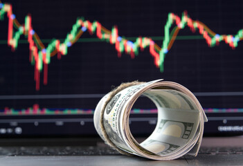 Hundred-dollar bills against a crypto exchange chart.