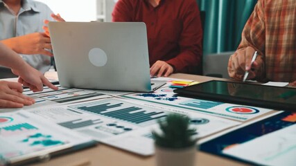 Professionals engaged in a collaborative meeting analyzing graphs and charts on laptops and tablets, highlighting teamwork in a modern office setting focused on digital marketing. SACTR - Powered by Adobe