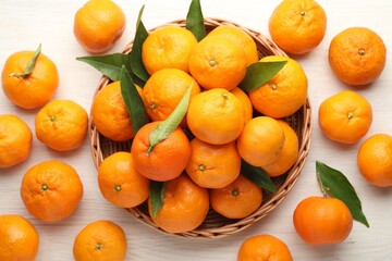 Fresh tangerines and green leaves on white wooden table, flat lay