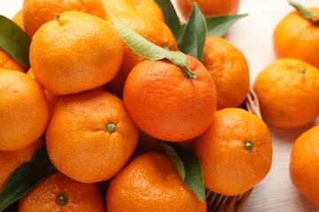 Fresh tangerines and green leaves on table, closeup