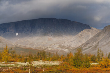 A Picturesque Mountain Valley Under a Stormy Sky with Autumn Colors and a Rare Forest Against a Mountainous Landscape