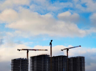 Three building cranes on a construction site background