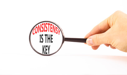 Consistency is the key symbol. Concept words Consistency is the key on beautiful magnifying glass. Businessman's hand. Beautiful white background. Business consistency is the key concept. Copy space.