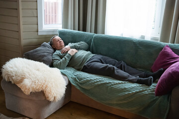 Mature man lying on sofa and resting at home, relaxing in cozy living room interior with natural daylight. Home Leisure Activities