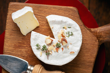 Cheese platter with brie or camembert cheese served with chopped almonds and baguette slices on wooden board