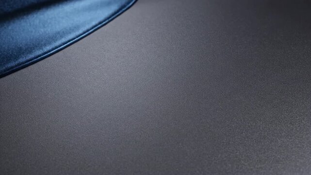 A close-up view of a denim fabric edge on a dark gray surface with subtle texture and soft lighting