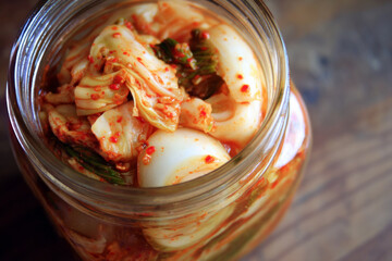 A detailed close-up photograph of traditional Korean kimchi featuring fermented cabbage with spices, presented as part of healthy Korean cuisine and table setting.