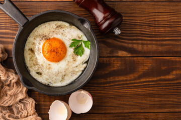 One egg cooked in a cast iron pan on wooden  background