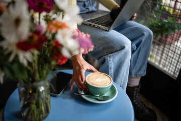 Woman drinking coffee working remotely in cafe