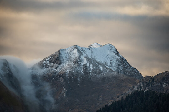 Snow-Capped Mountain Peak in Metsovo, Pindus Range, Greece - Dramatic Alpine Landscape with Low Clouds and Mist at Sunset