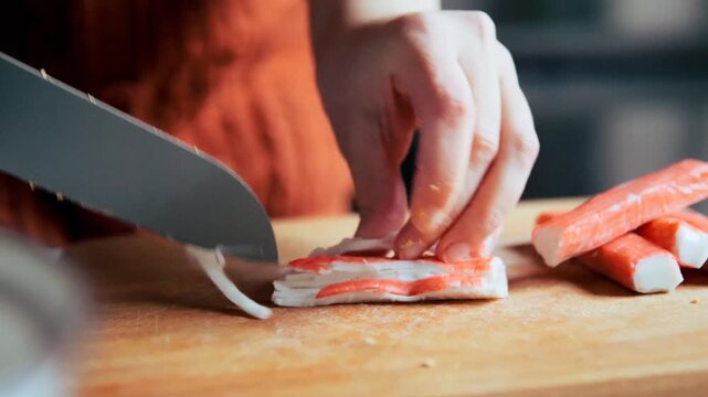 Hands Mincing Imitation Crab surimi Sticks on a Wooden Cutting Board