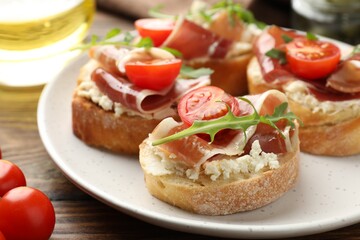 Delicious bruschettas with cream cheese, prosciutto, tomatoes and arugula on table, closeup