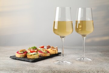 White wine in glasses and bruschette on grey table