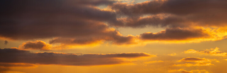 Warm sunset sky with soft glowing clouds and golden light. Peaceful evening atmosphere, natural background with copy space, perfect for nature and travel concepts.