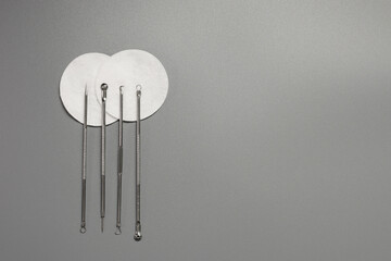 Metal tools for cleaning skin with acne or blackheads. Needles for closed comedones on a gray background. Copy space.