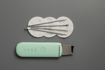 Ultrasonic facial cleansing tools. Remove blackheads. Skin care kit for a cosmetologist on a gray background.