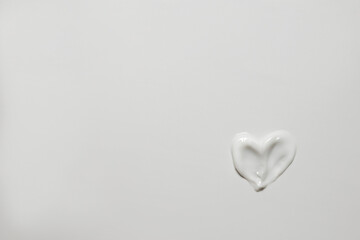 White background with copy space and heart-shaped skin cream. Empty backdrop for cosmetology and dermatology concept.