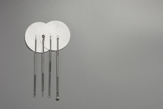 Metal tools for cleaning skin with acne or blackheads. Needles for closed comedones on a gray background. Copy space.