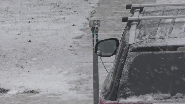 A car with engine block heater cable plug outside in winter