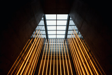 Modern glass atrium with glowing amber lights viewed upward