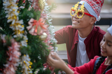 The children are celebrating Christmas and decorating the Christmas tree together.