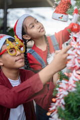 The children are celebrating Christmas and decorating the Christmas tree together.