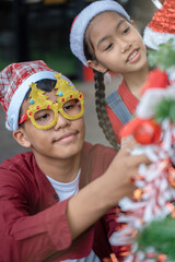 The children are celebrating Christmas and decorating the Christmas tree together.