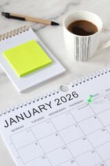 January first 2026 new year calendar date with a pin on white table with coffee cup, notebook, and...