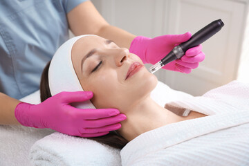 Woman undergoing microneedling procedure in beauty salon, closeup