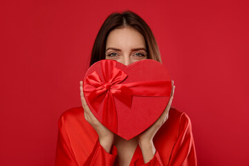 St. Valentine's Day. Beautiful woman with gift on red background