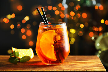 Refreshing spritzer cocktail, mint and orange slice on wooden table in bar, closeup