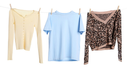 Different clothes drying while hanging on clothesline against white background