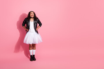 Portrait of a gay nonbinary person in a tutu and leather jacket against a pink backdrop, celebrating individuality, queer fashion, and pride