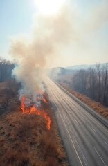 Fototapeta premium Aerial view of a dry grass fire burning next to a busy highway. Thick smoke rises into the sky. Vehicles travel on the road oblivious to the danger.