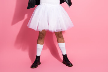 Homosexual nonbinary man in a ballerina dress with a leather jacket stands on a pink pastel background