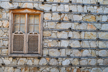 Handcrafted wooden window detail with motifs on a traditional buttoned house wall.