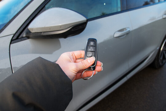 Car remote control by smart key, female Hand holding smart key to lock doors of grey car