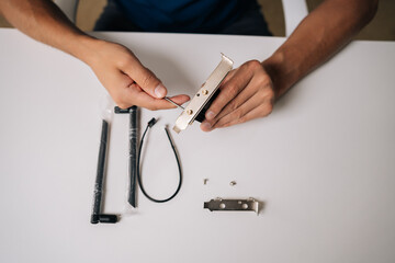Top view of technician assembling wi-fi module with heatsink preparing to installing into computer, upgrading wireless network card for improved connectivity. Concept of desktop PC maintenance